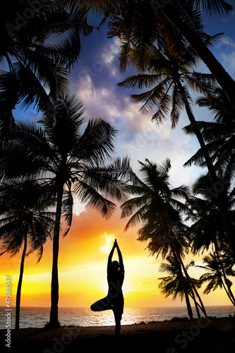 Yoga tree pose around palm trees photo