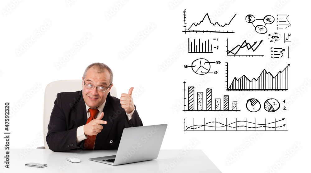 Businessman sitting at desk with diagrams and laptop