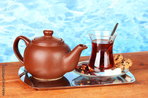 glass of Turkish tea and kettle on color background © Africa Studio