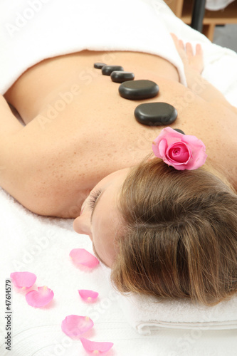 beautiful young woman in spa salon with spa stones, close up