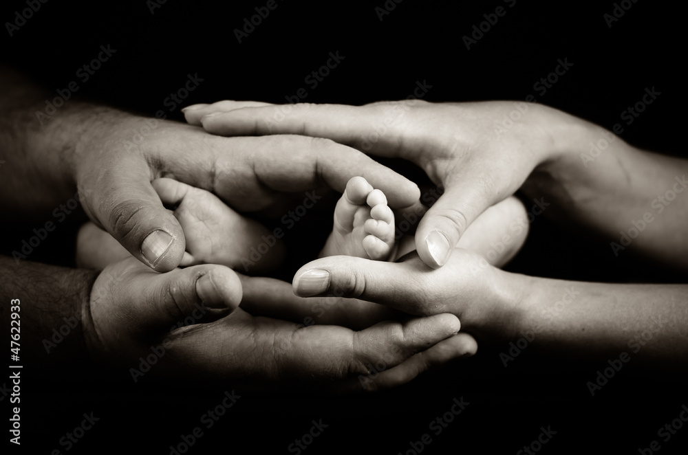 Mother and father holding little newborn's feet Mother and father holding little newborn's feet