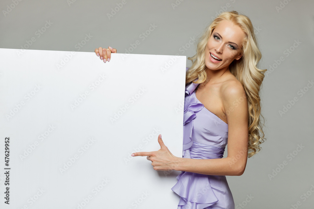 Woman pointing at a blank board over gray background Woman pointing at a blank board over gray background