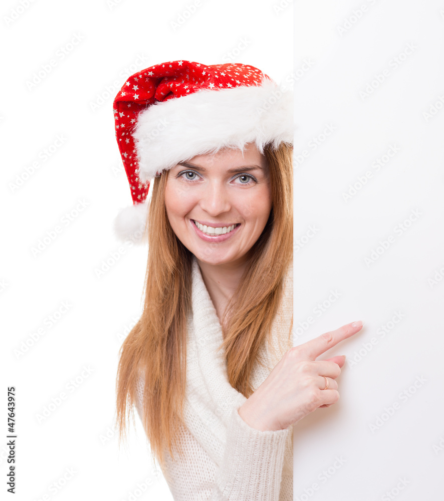Young woman wearing Santa Claus hat and pointing to the blanc bo Young woman wearing Santa Claus hat and pointing to the blanc bo