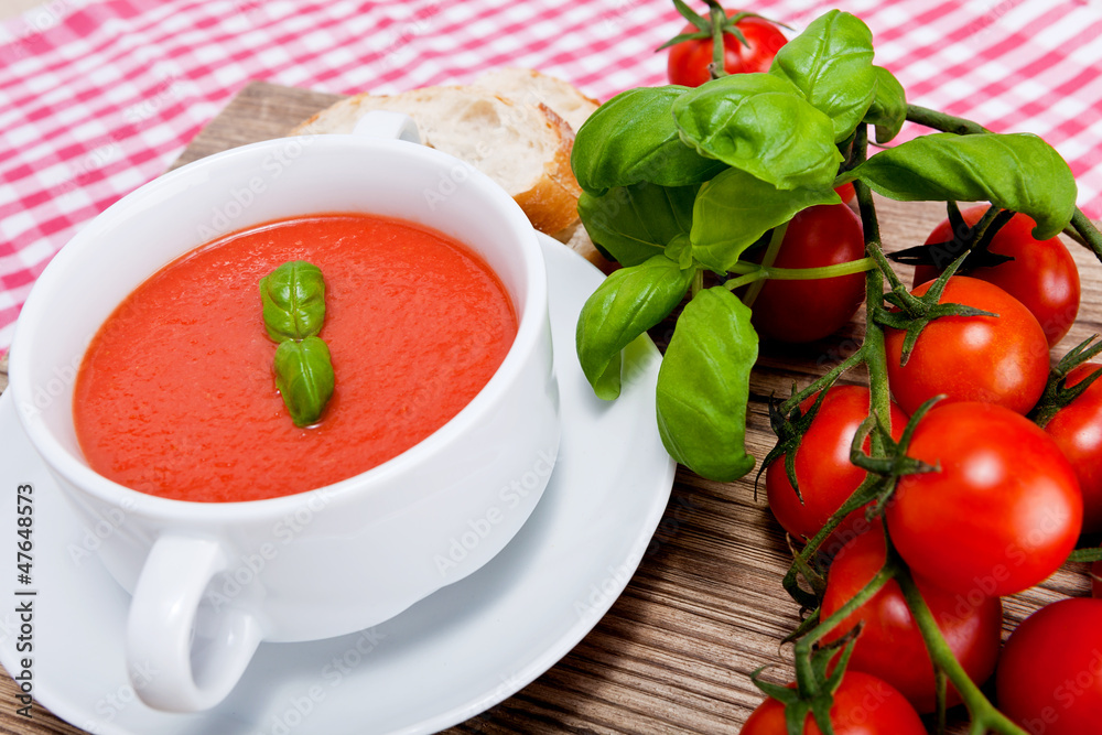 Frische tomatensuppe in einer weißen suppentasse mit basilikum Frische tomatensuppe in einer weißen suppentasse mit basilikum
