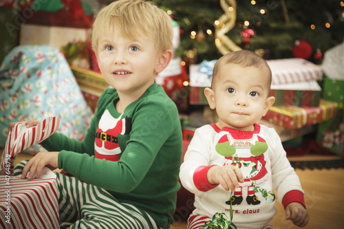 Baby and Young Boy Enjoying Christmas Morning Near The Tree