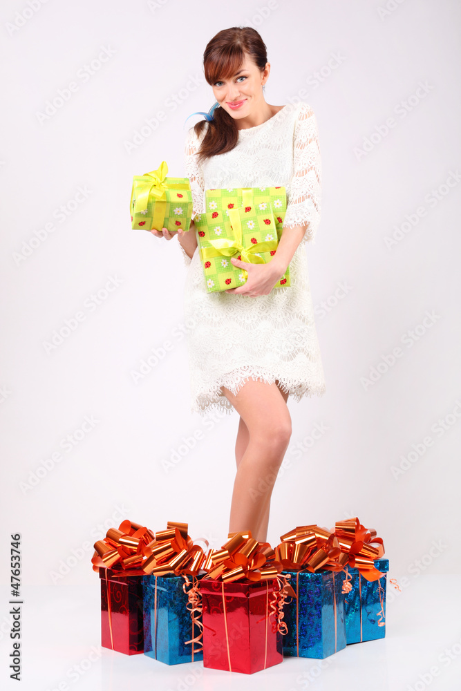 Happy girl holds boxes with gifts, stands among gift boxes Happy girl holds boxes with gifts, stands among gift boxes