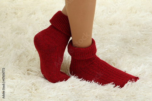 Female legs in colorful socks on  white carpet background