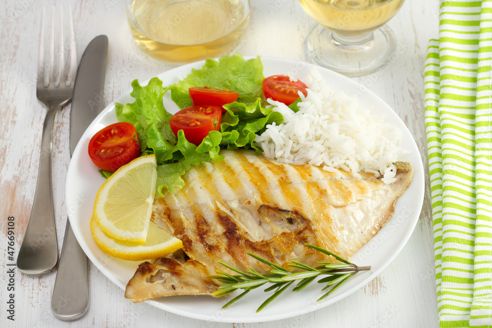 grilled fish with rice ans salad on the white plate