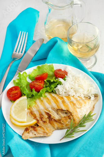 fish with rice and salad on the plate and glass of wine