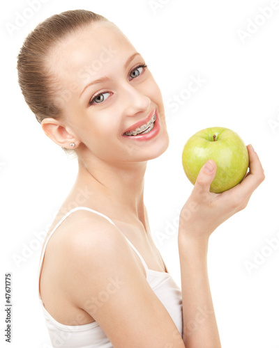 Cute girl in braces with green apple on white background