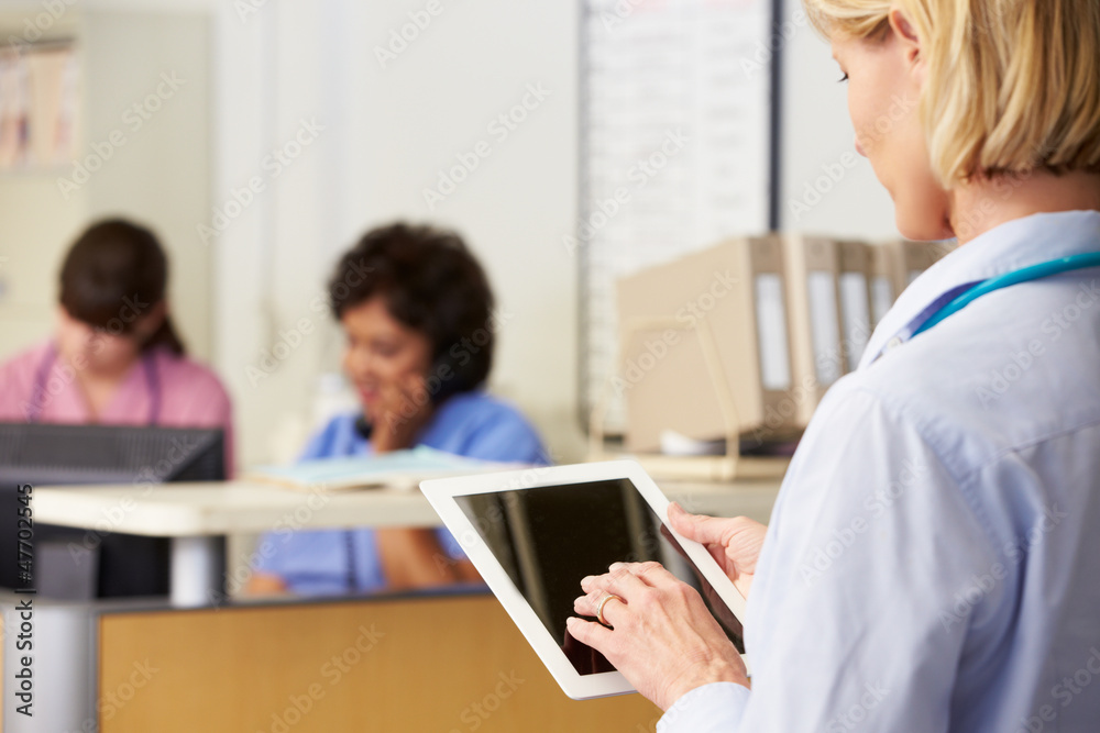 Female Doctor Using Digital Tablet At Nurses Station Female Doctor Using Digital Tablet At Nurses Station
