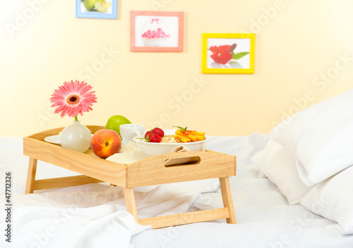 wooden tray with light breakfast on bed