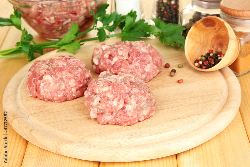 Raw meatballs with spices on wooden table