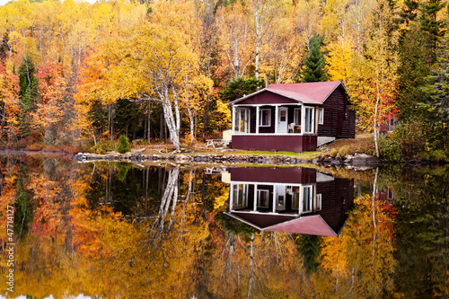 Reflections of a autumn forest and a house in a lake