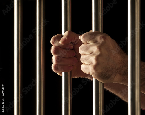hands of a prisoner behind bars