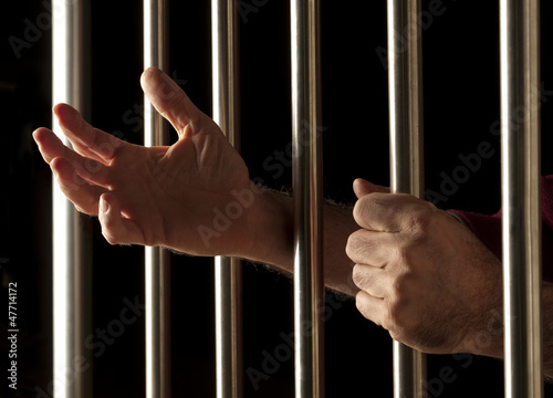 hands of a prisoner behind bars
