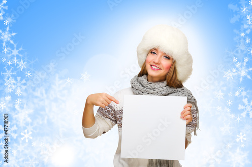 Young smiling girl with empty card on snowy background