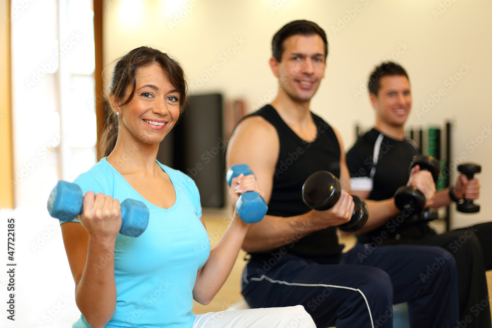 Group of three people training with gymnastic balls and dumbbell