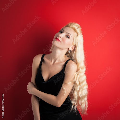 Beautiful blonde woman close up portrait against red background.