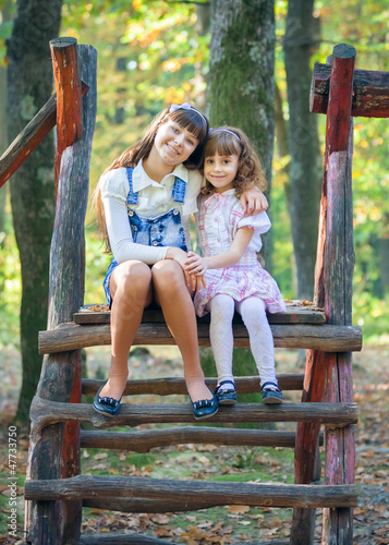 Happy little sisters on swing in park © Andriy Petrenko
