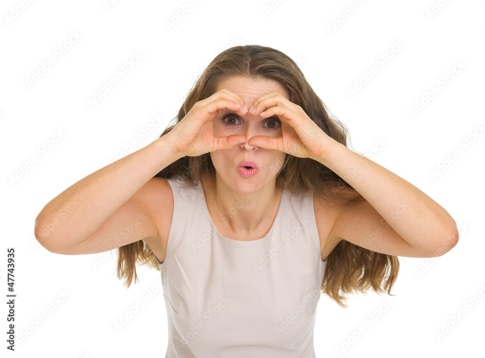 Surprised young woman looking through binoculars shaped hands Surprised young woman looking through binoculars shaped hands
