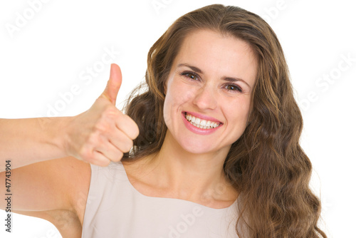 Portrait of smiling young woman in dress showing thumbs up