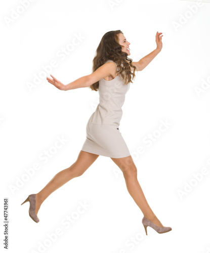 Young woman in dress jumping. Side view