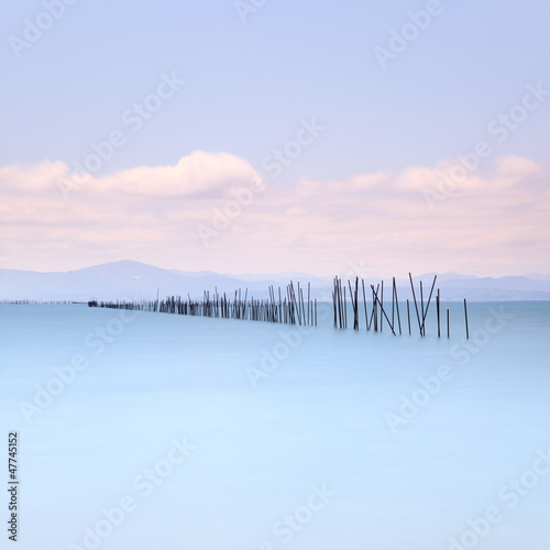 Fishing poles and soft water on sea landscape. Long exposure. © stevanzz