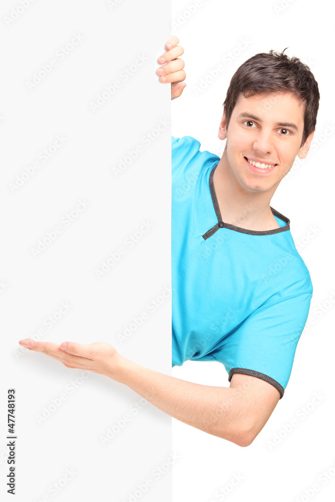 A smiling handsome male gesturing behind a panel A smiling handsome male gesturing behind a panel
