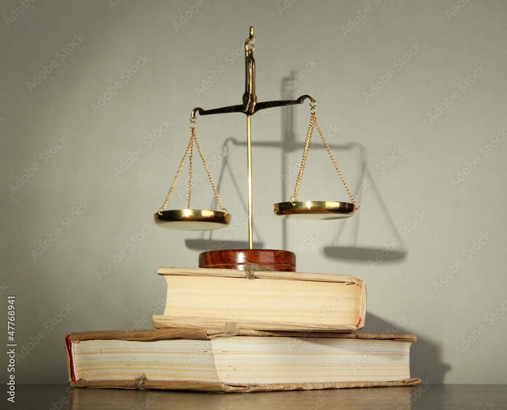 Gold scales of justice and books on grey background Gold scales of justice and books on grey background