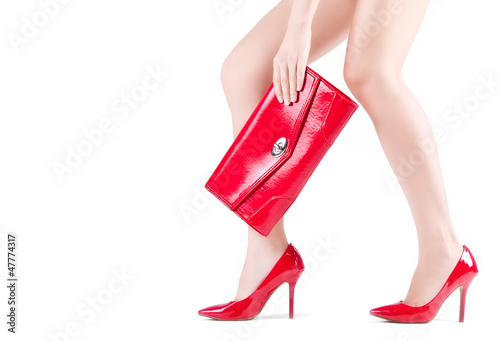 Beautiful slender womanish feet in red shoes and mini bag