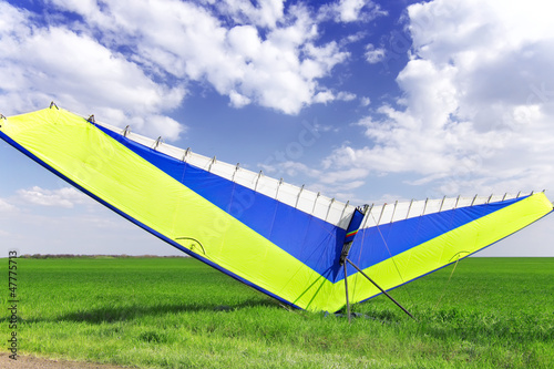 Motorized hang glider over green grass