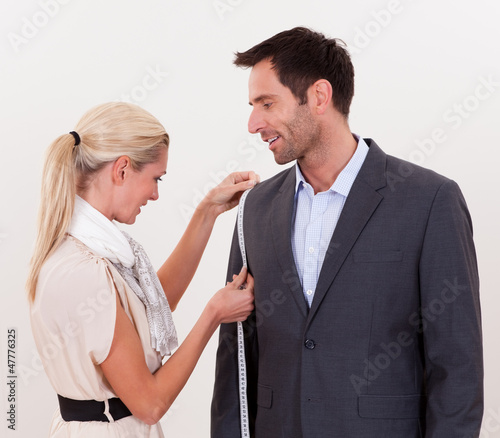Seamstress measuring a man for a suit