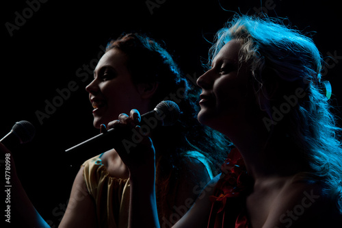 Two women singing in microphone