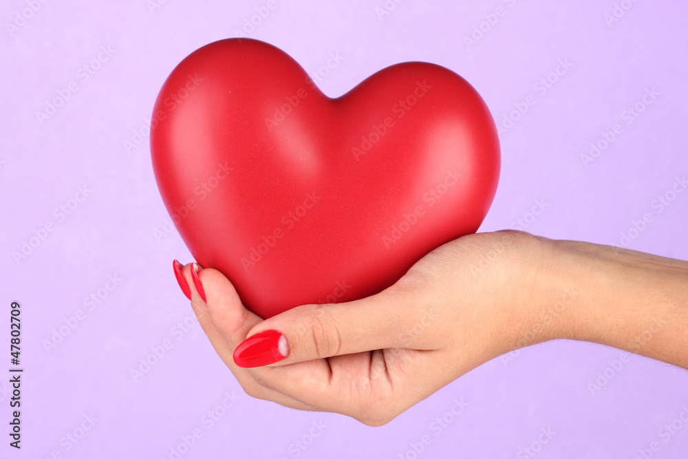 Red heart in woman's hand on color background Red heart in woman's hand on color background