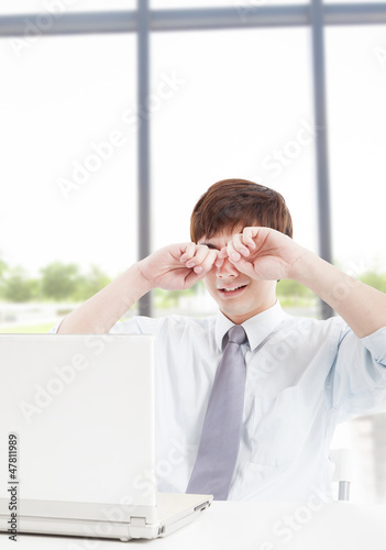 Young businessman with tired eyes and working in office