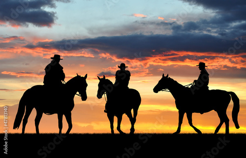 Silhouette cowboys with horses in the sunset