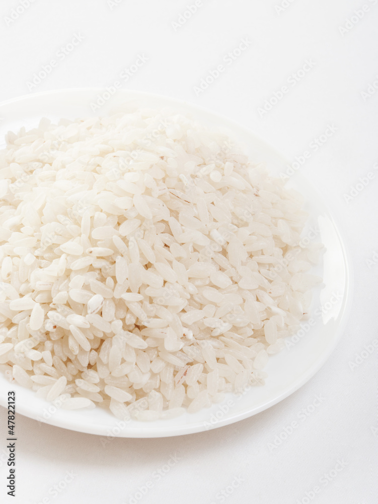 Uncooked rice in a ceramic plate on white background Uncooked rice in a ceramic plate on white background