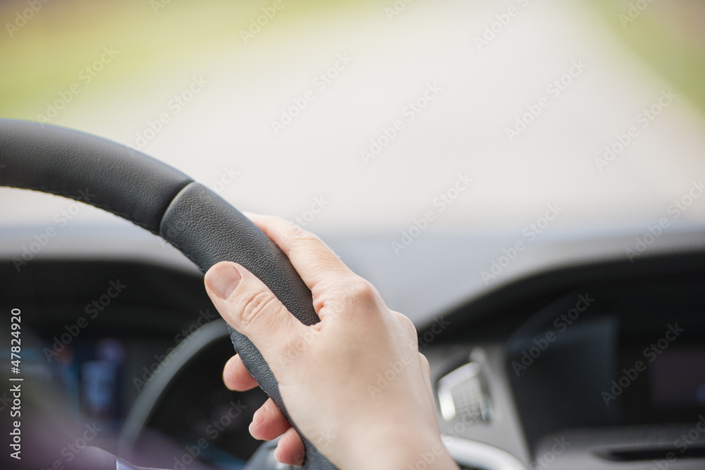 Hand of woman on steering wheel inside car