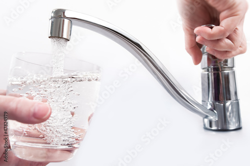 Wasserglas wird am Wasserhahn gefüllt