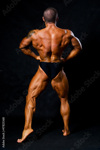 Tanned bodybuilder shows muscles of arms and back