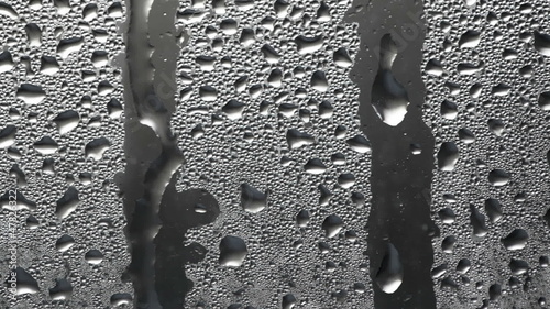 Flowing down water drops on glass