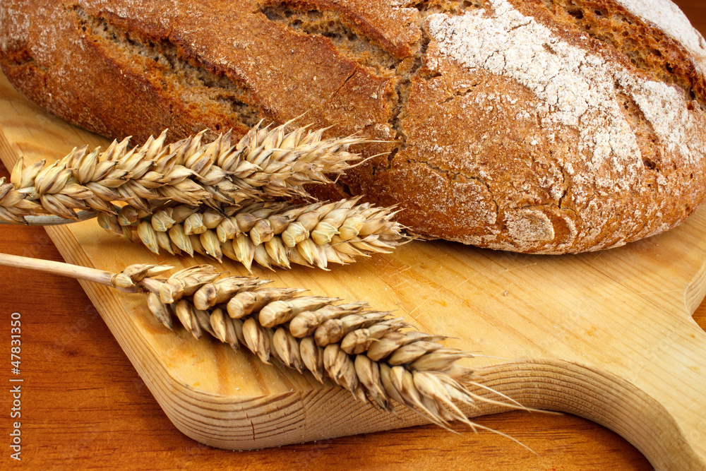 Fresh baked loaf with wheat ears on table