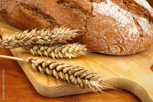 Obraz na płótnie Fresh baked loaf with wheat ears on table w salonie