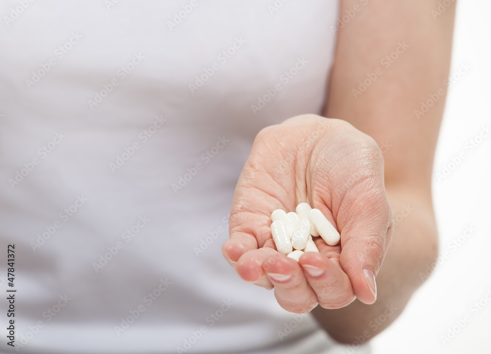Human hand holding heap of pills