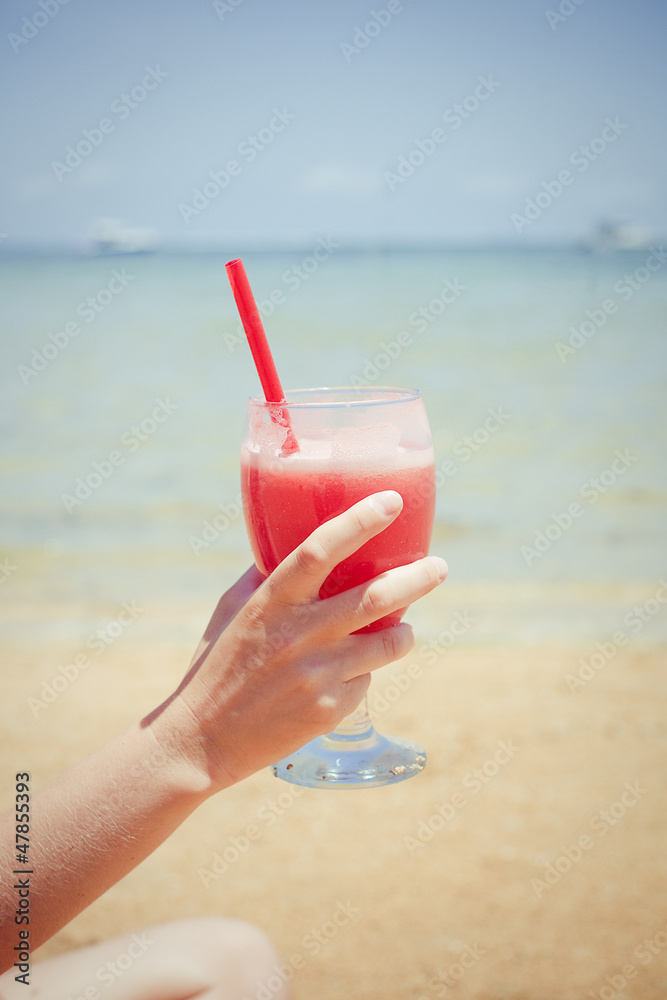 relaxing woman sitting on sand with cocktail 