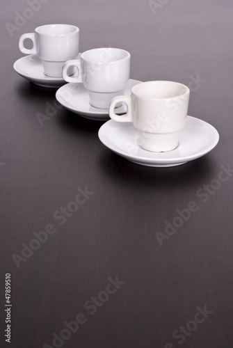 3 white coffee cups on brown table