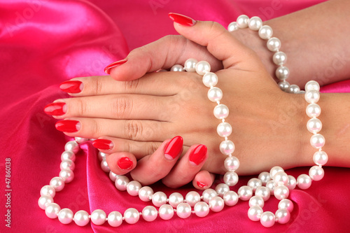 Female hands holding beads on color background