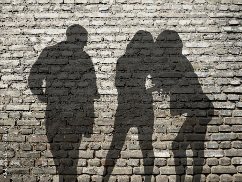 ombres 1 homme 2 femmes sur mur de briques Photos | Adobe Stock