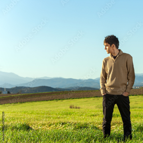 Young man standing in green field. © karelnoppe